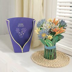 a vase filled with flowers sitting on top of a table next to a blue bag