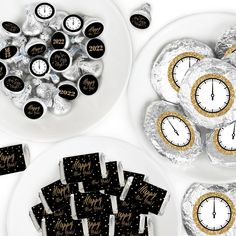 chocolate covered candies with black and gold foil wrappers in front of white plates