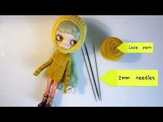 the doll is next to two needles and yarn