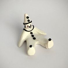 a white ceramic figurine with black eyes and a hat