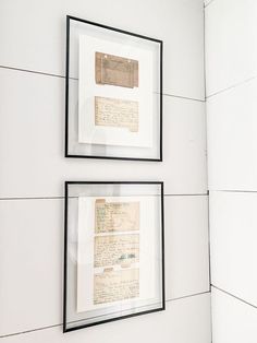 two framed papers are hanging on the wall next to each other in black and white frames