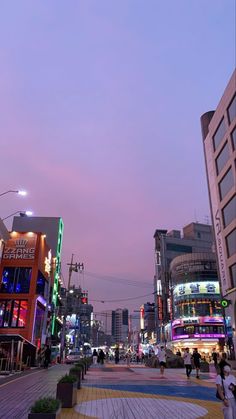 a city street filled with lots of tall buildings and people walking on the side walk