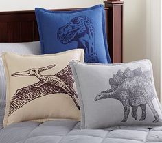 three pillows on a bed with an image of a bird and a giraffe