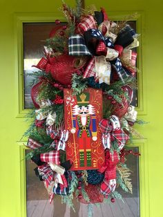 a red and black christmas wreath with a nutcracker figure on the front door