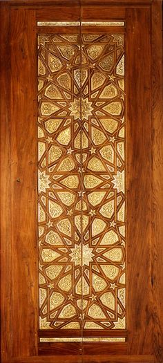 an intricately carved wooden door with gold foil on it's glass inserts