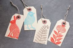 four tags with different designs on them are hanging from clothes pins and hangers in the shape of animals