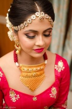 a woman in a red dress with gold jewelry on her neck and headpieces