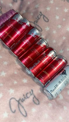 six cans of energy drink sitting on top of a pink bed sheet with stars print