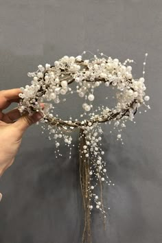 a hand holding a white flower crown with baby's breath