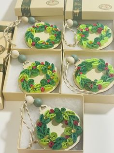 four christmas wreaths in boxes with string and buttons on the top one is green