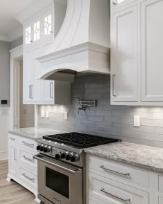 a stove top oven sitting inside of a kitchen next to white cabinets and counter tops