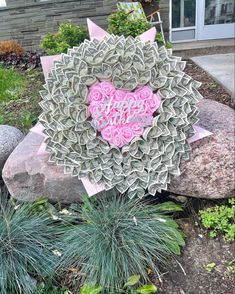 a heart made out of money sitting on top of a rock