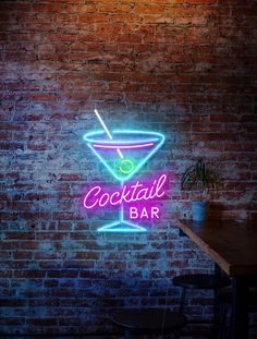 a neon sign that says cocktail bar on a brick wall in front of a table