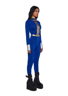 a woman in a blue jumpsuit with gold accents on her chest and black boots