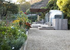 an outdoor hot tub in the middle of a garden with lots of flowers and trees