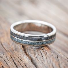 two wedding bands are sitting on top of a piece of wood