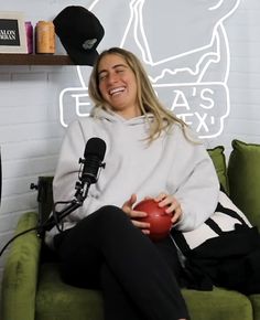 a woman sitting on top of a green couch holding a red ball