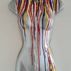 a white mannequin with multicolored paint dripping down it's body