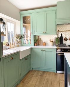 a kitchen filled with lots of green cabinets and white counter top space next to a window