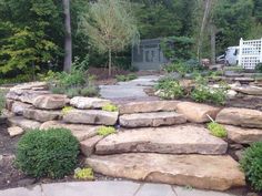 a garden with large rocks and trees in the background