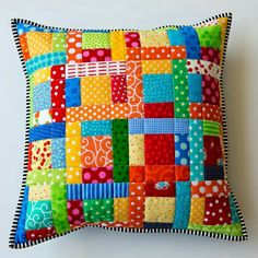 a colorful patchwork pillow on a white wall