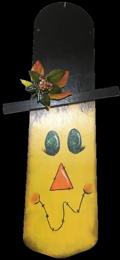 a yellow and black sign with a face on it's side, hanging from a metal hook