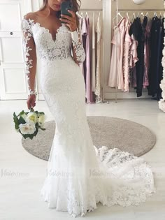 a woman in a wedding dress taking a selfie with her cell phone while looking into the mirror