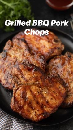 grilled pork chops on a black plate with garnish