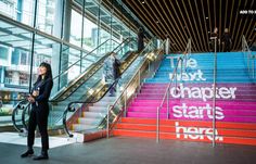 two women walking up and down the stairs in an office building with colorful banners on them