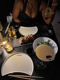 a woman sitting at a table with plates and bowls of food in front of her