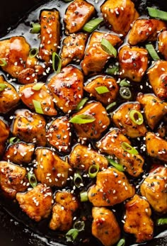 chicken with sesame seeds and green onions in a skillet, ready to be eaten