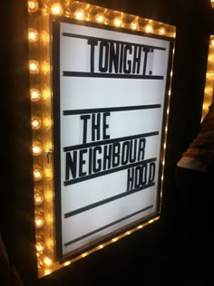 there is a sign that says tonight and the neighbourhood hold it up with lights around it