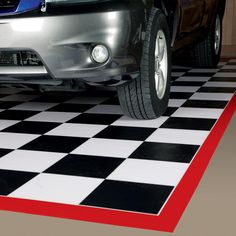 a car is parked on a checkered black and white floor with red line in the middle