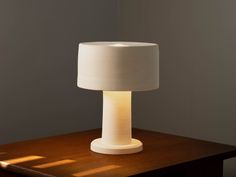 a white lamp sitting on top of a wooden table