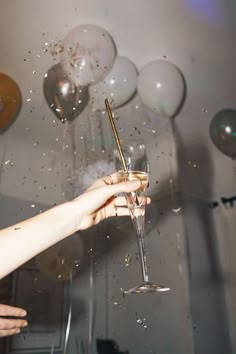 a woman holding a wine glass in front of balloons and confetti on the wall