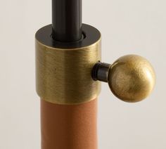 a close up of a gold and black object on a white background with an orange ball