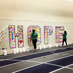 two women are standing in front of a wall with the word hope painted on it