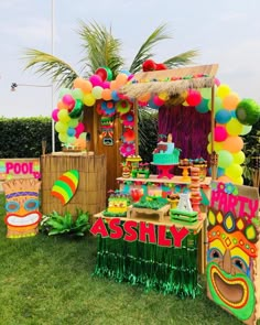 a table with decorations and balloons on it in the middle of a lawn area at a birthday party