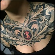 a woman's chest with an ornate design and skull in the center on it