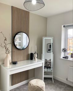 a room with a table, mirror and vase on it