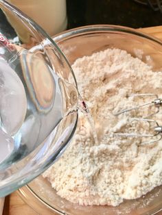 a glass bowl filled with flour next to a whisk