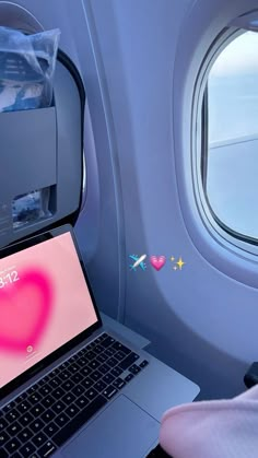 a laptop computer sitting on top of an airplane seat next to a heart sticker