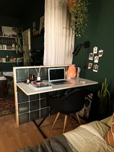 a desk with two laptops on it in front of a window and a bed