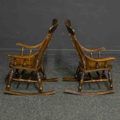 two wooden rocking chairs sitting next to each other on top of a carpeted floor