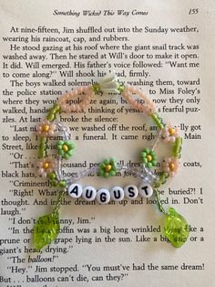 a bracelet with beads and charms on top of an open page in the book about august