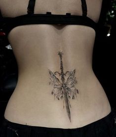 a woman's lower back tattoo with a knife and flowers on the side,