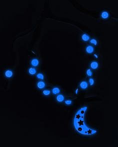 a blue necklace with stars and moon on it in the dark, lit up at night