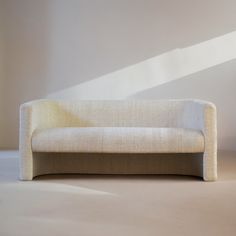 a white couch sitting on top of a floor next to a window in a room