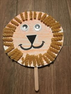 a paper plate with a lion face and some pasta on it, sitting on a wooden table