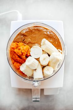 a food processor filled with bananas and other ingredients on top of a white countertop